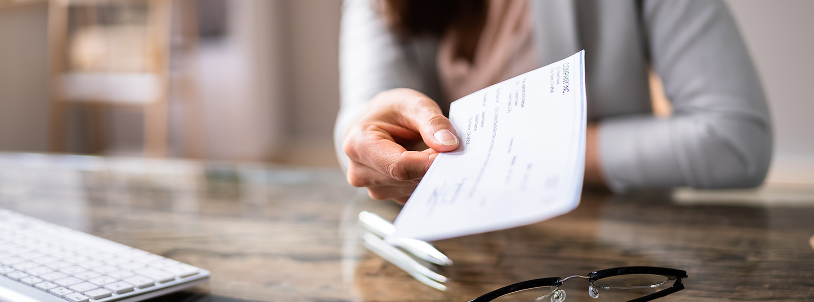 A lady holding out a check at her desk